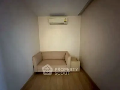 Cozy small living area with beige sofa and air conditioning unit, perfect for compact spaces.
