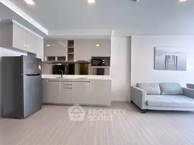 Modern open-layout kitchen and living room with sleek cabinetry and cozy sofa.