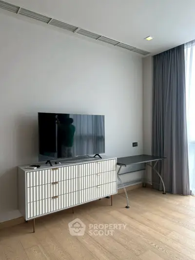 Modern living room with sleek TV stand and large window for natural light.