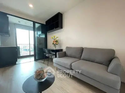 Modern living room with gray sofa and balcony view in a stylish apartment.