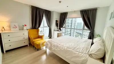 Spacious bedroom with city view, elegant decor, and natural light in modern apartment.