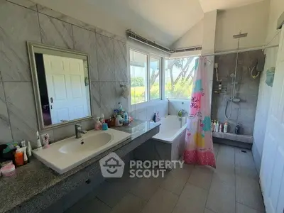 Spacious bathroom with bathtub and shower, featuring large windows and modern fixtures.