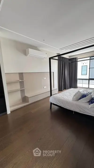 Spacious modern bedroom with elegant four-poster bed and large window for natural light.