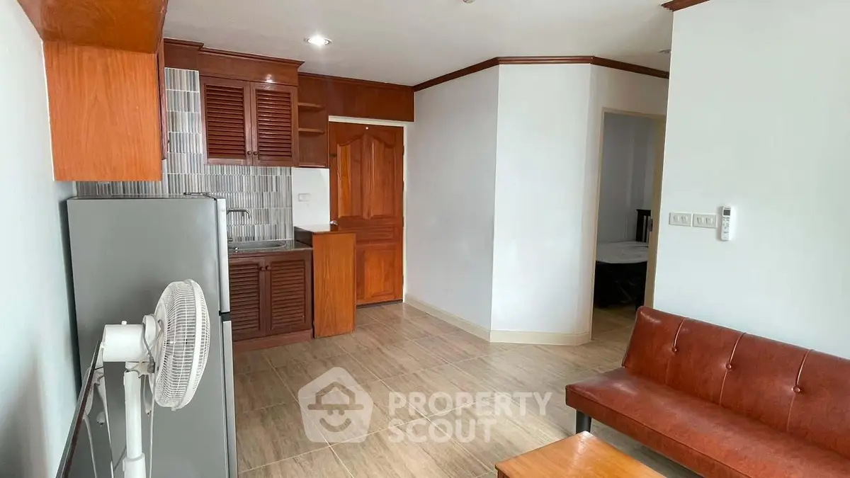 Cozy living room with wooden accents and compact kitchen area in modern apartment.