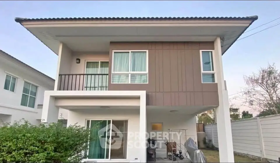 Modern two-story house with balcony and spacious driveway in suburban neighborhood.