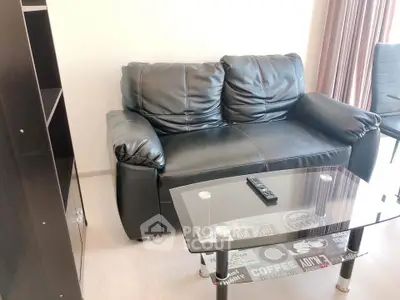 Modern living room with black leather sofa and glass coffee table, perfect for cozy relaxation.