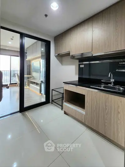 Modern kitchen with sleek cabinetry and open layout leading to a bright living area with balcony view.