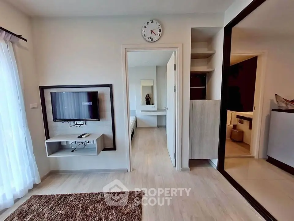 Modern apartment interior with wall-mounted TV and open view into bedroom