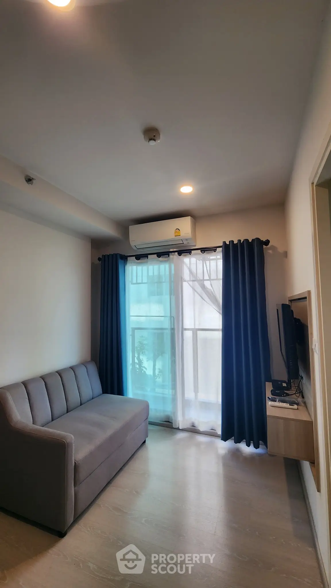 Modern living room with sofa, TV, and balcony view in a stylish apartment.