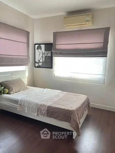 Cozy bedroom with modern decor and air conditioning, featuring stylish window treatments and hardwood flooring.