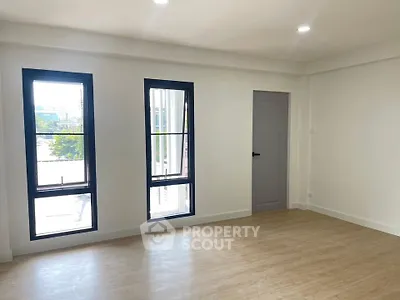 Spacious and bright room with large windows and wooden flooring, perfect for modern living.