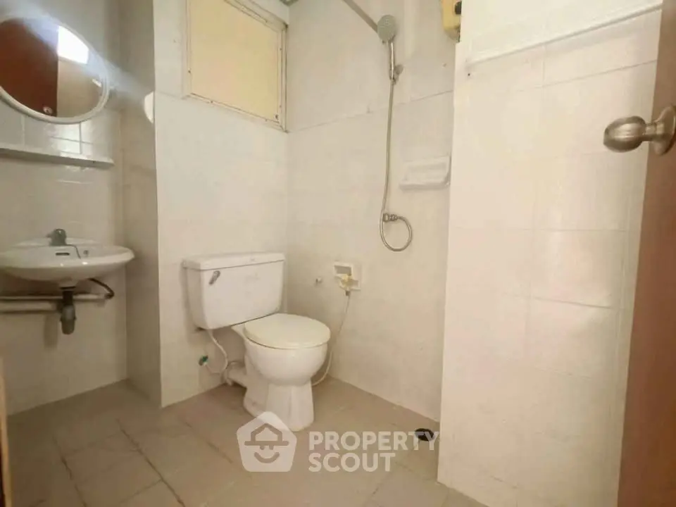 Compact bathroom with shower, toilet, and sink in minimalist design.