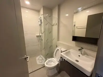 Modern bathroom with glass shower and sleek fixtures in contemporary apartment.