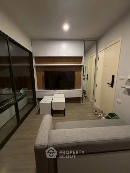 Modern living room with sleek furniture and large glass doors leading to a balcony.
