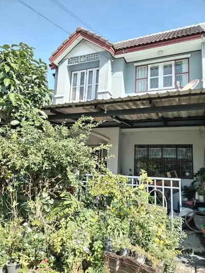 Charming two-story house with lush garden and classic architectural design.