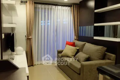 Cozy living room with modern decor and large window draped with elegant curtains.