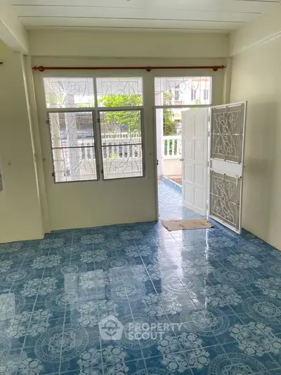 Bright living room with blue patterned tile flooring and large windows opening to a balcony.