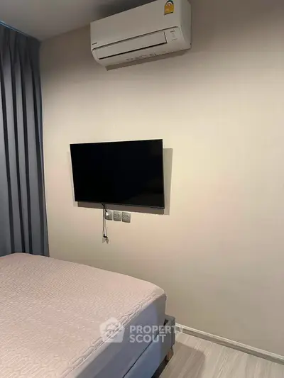 Modern bedroom with wall-mounted TV and air conditioning unit, perfect for comfortable living.