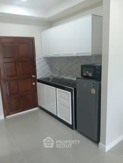 Modern compact kitchen with sleek cabinetry and stainless steel appliances in a cozy apartment.