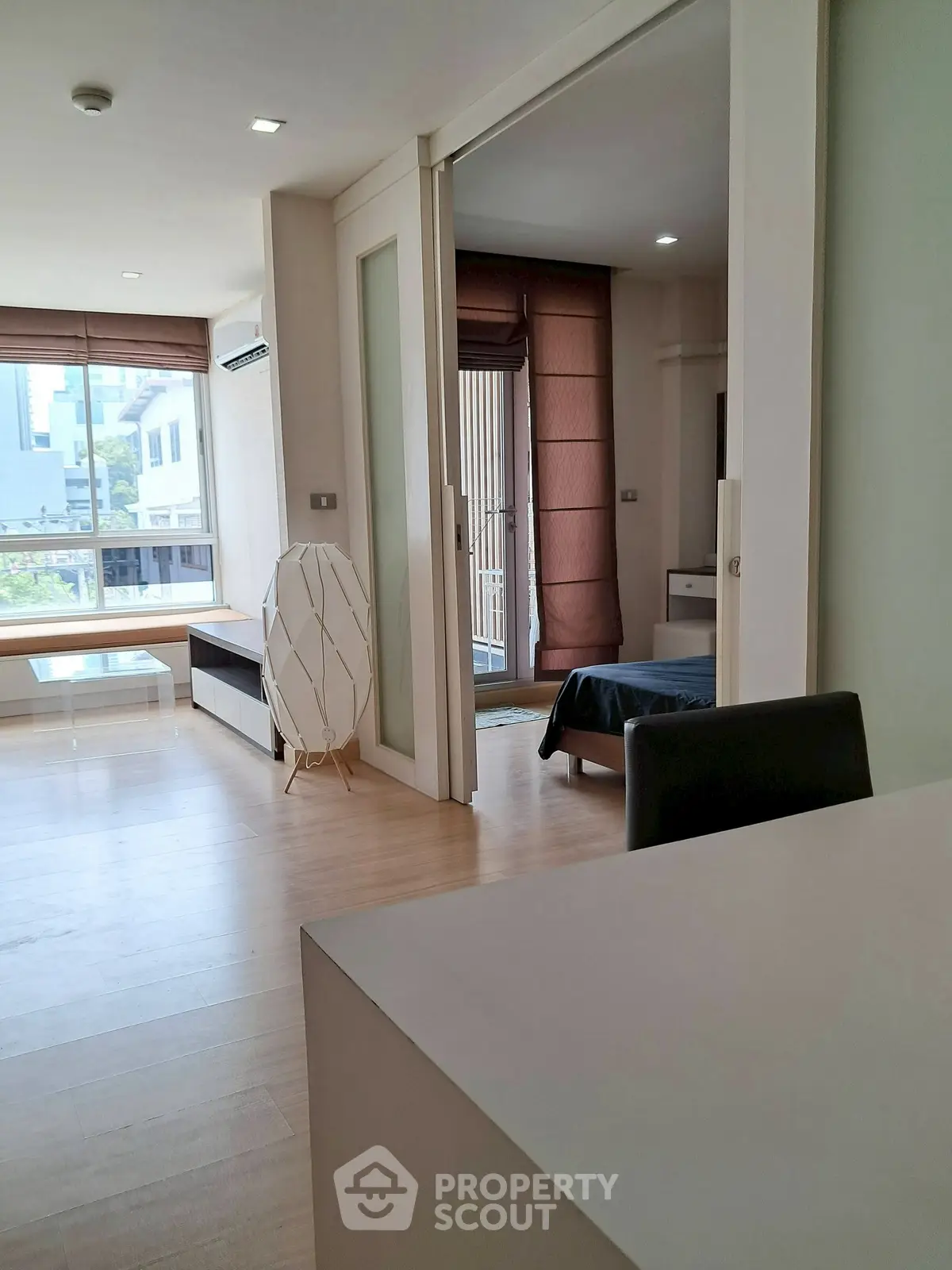 Modern open-plan living room with sliding doors leading to a cozy bedroom, featuring natural light and stylish decor.