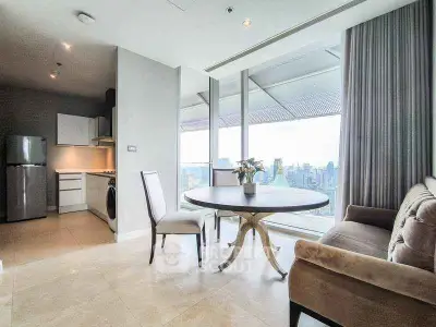 Modern living room with city view, featuring elegant furniture and open kitchen layout.