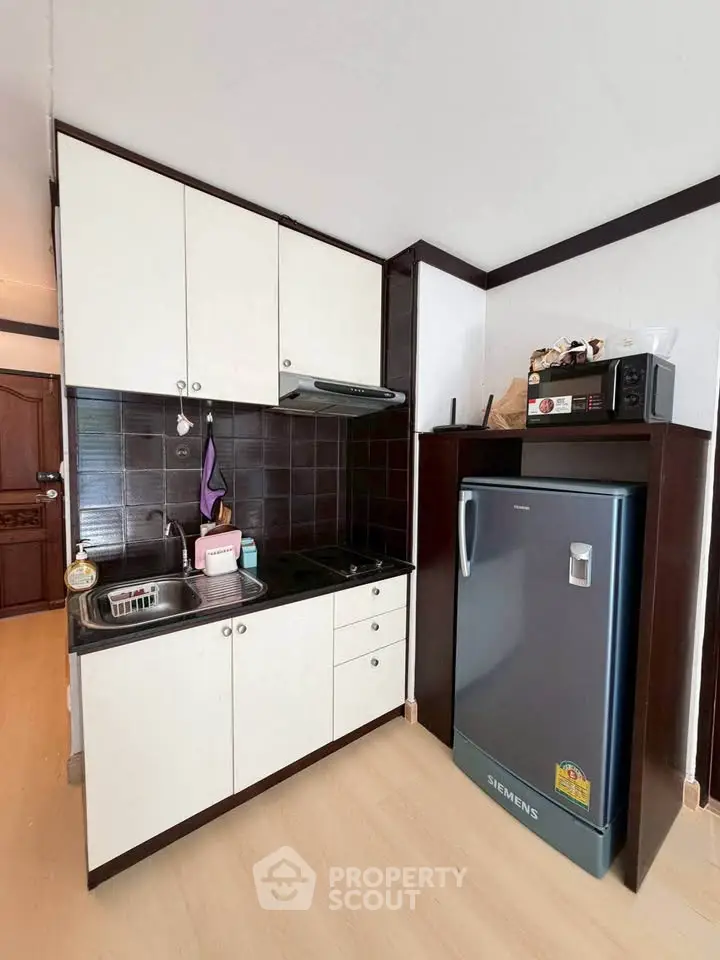 Compact kitchen with modern appliances and sleek cabinetry in a cozy apartment.