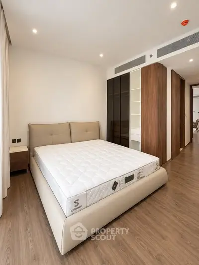 Spacious modern bedroom with elegant wooden flooring and stylish furniture