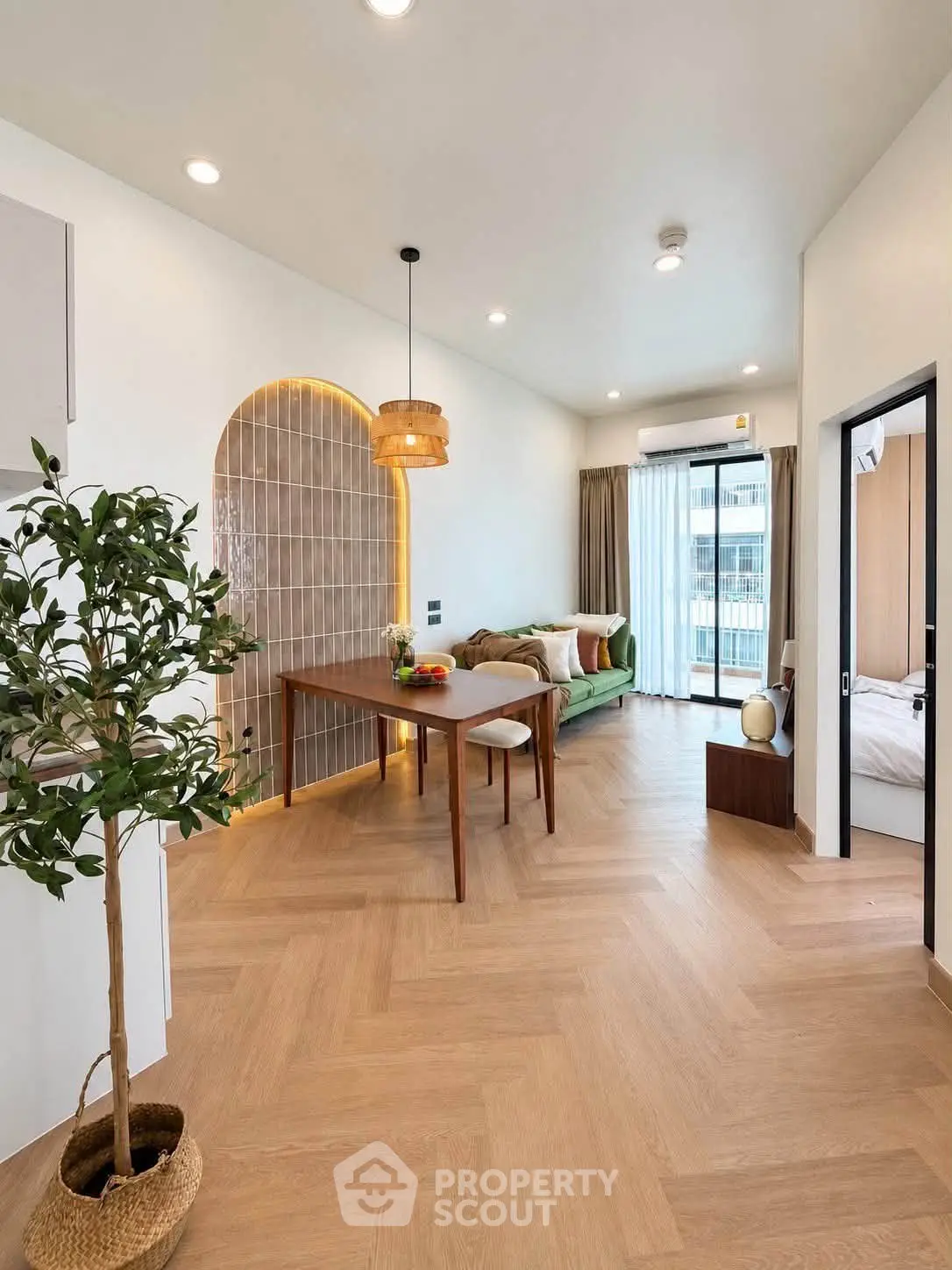 Modern living room with stylish decor and wooden flooring, featuring a cozy dining area and large windows.