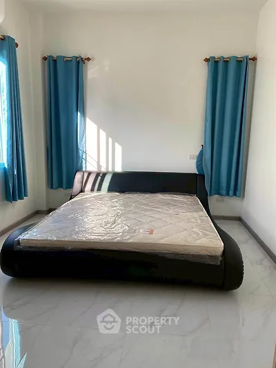 Spacious bedroom with modern bed and blue curtains, perfect for relaxation.