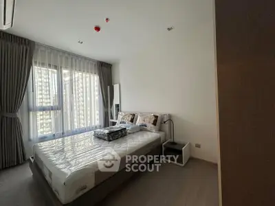 Modern bedroom with large window and stylish decor in a high-rise apartment.