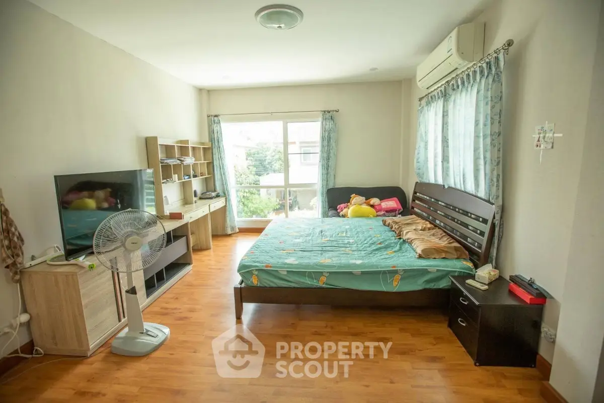 Spacious bedroom with large window and modern furnishings, ideal for comfort and relaxation.