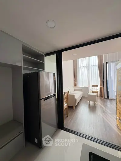 Modern apartment with open layout, featuring a sleek kitchen and bright living area with large windows.