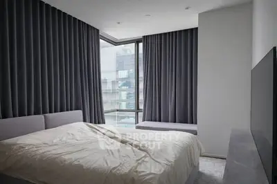 Modern bedroom with large windows and elegant curtains in a stylish apartment.