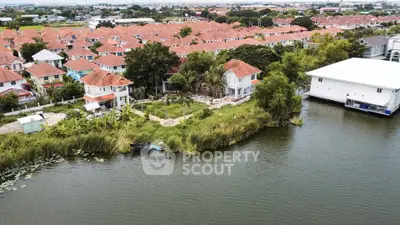 Scenic aerial view of waterfront homes with red roofs and lush greenery, ideal for serene living.