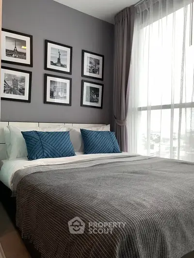 Modern bedroom with stylish decor and large window offering natural light.