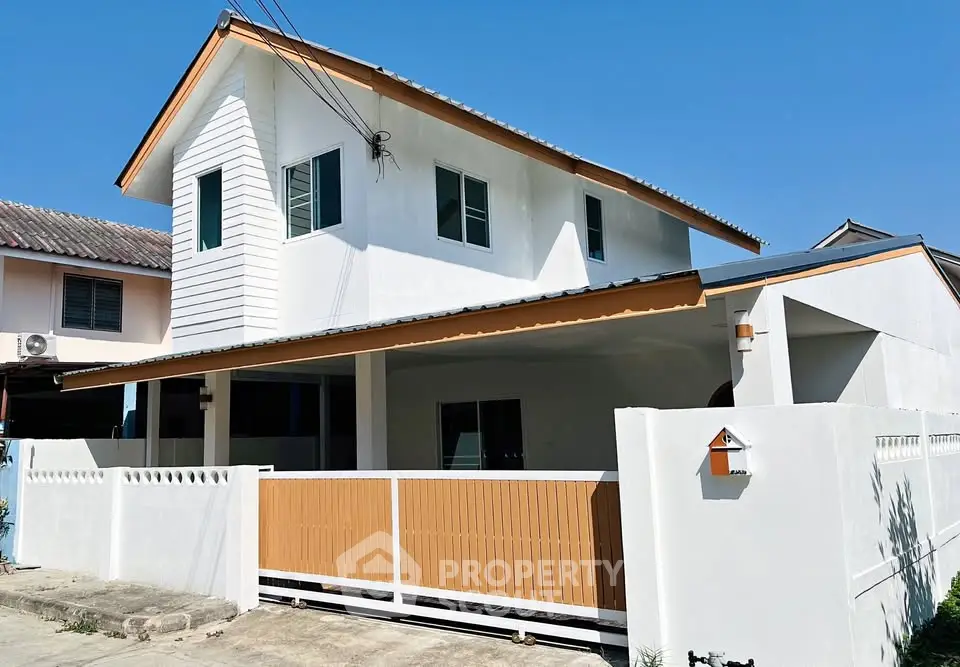 Modern two-story house with white facade and wooden accents under clear blue sky.