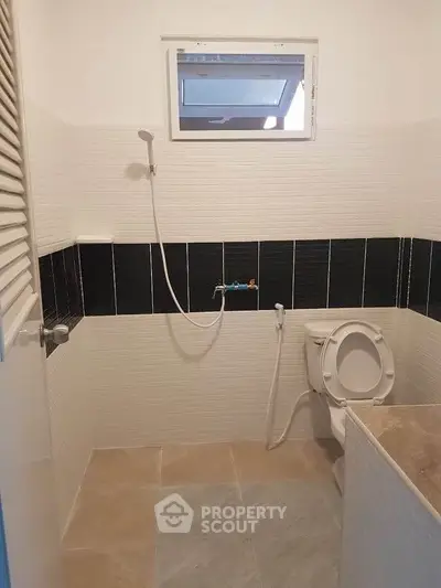 Modern bathroom with sleek black and white tiles and compact shower design.