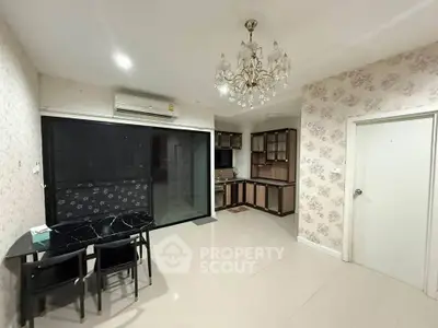 Spacious open-plan living area with elegant chandelier and modern kitchen.