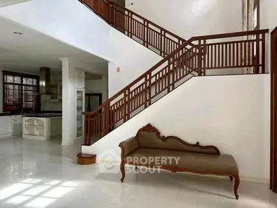 Elegant interior with wooden staircase and classic sofa in spacious living area