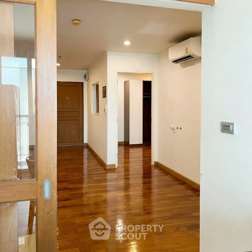 Spacious apartment hallway with wooden flooring and modern air conditioning unit.