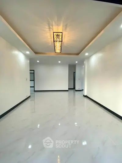 Spacious modern living room with elegant lighting and glossy tile flooring.