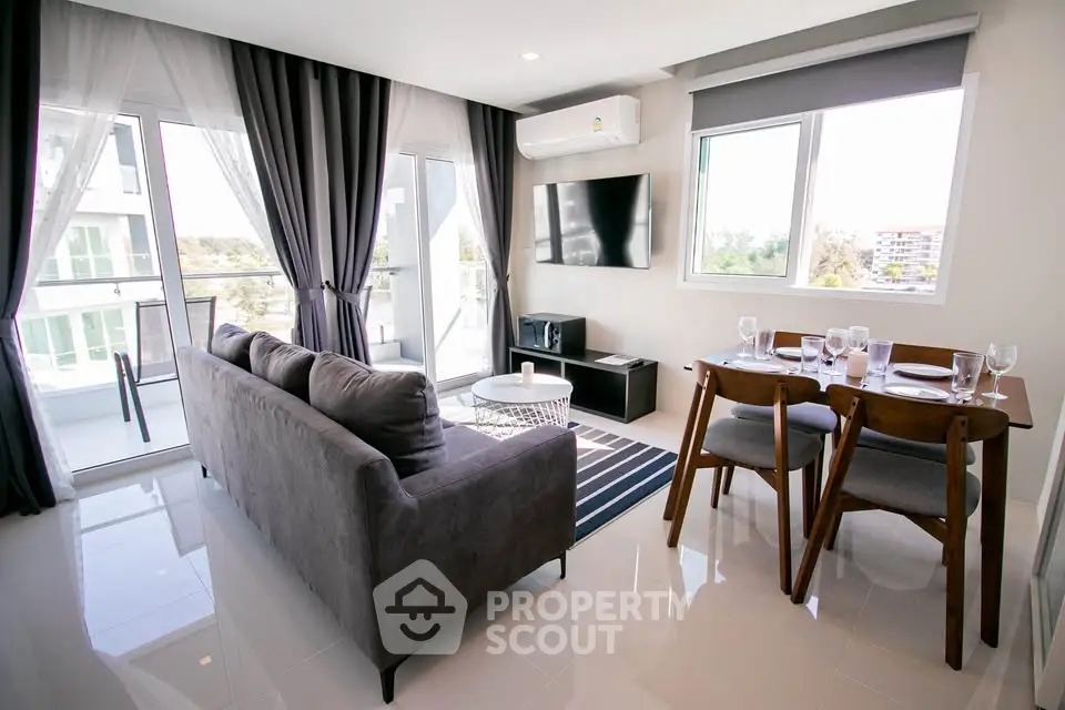 Modern living room with sleek furniture and large windows offering natural light and a view.