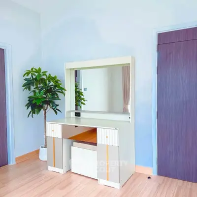 Modern bedroom with stylish vanity and potted plant, showcasing elegant design and natural light.