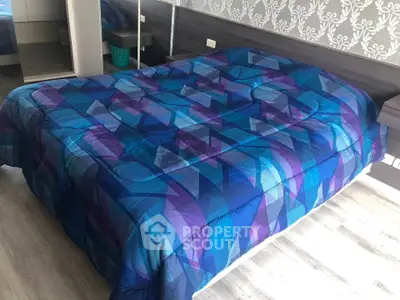 Modern bedroom with stylish geometric blue bedding and sleek wooden flooring.