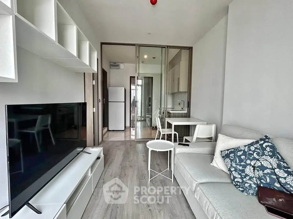 Modern living room with sleek furniture and open layout, featuring a large TV and stylish decor.
