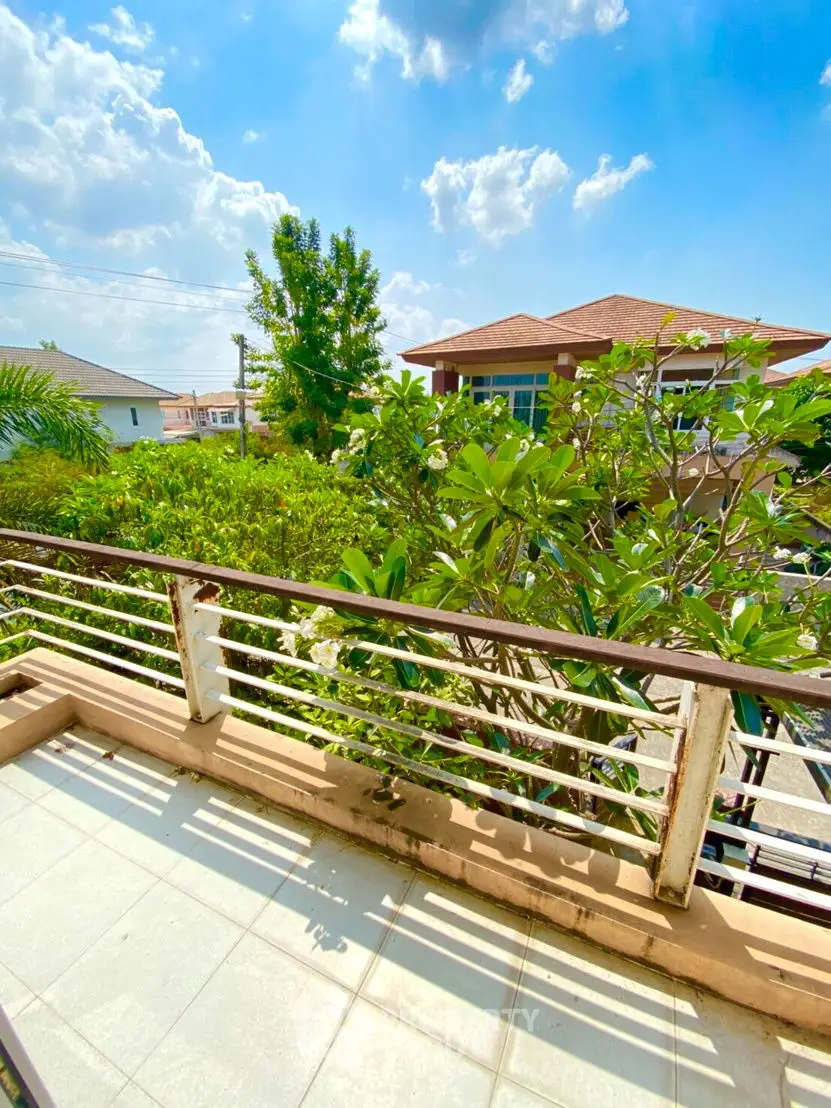Charming balcony with lush greenery and clear blue sky view, perfect for relaxation.