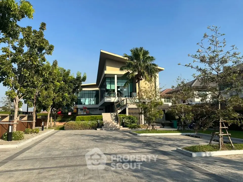Modern architectural house with lush garden and spacious driveway under clear blue sky.