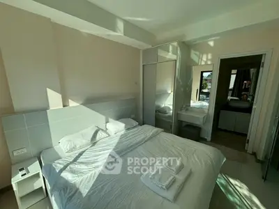 Spacious bedroom with modern design and ample natural light, featuring a comfortable bed and sleek furniture.
