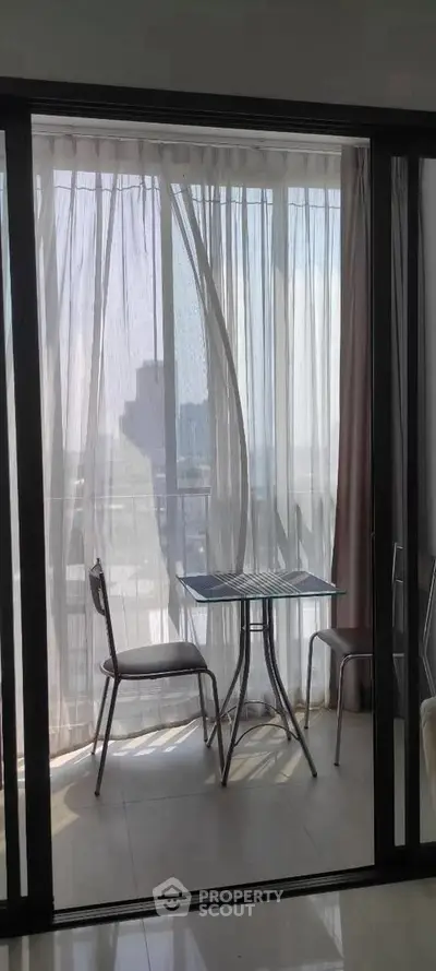 Charming balcony with sheer curtains and outdoor seating, offering a serene view.