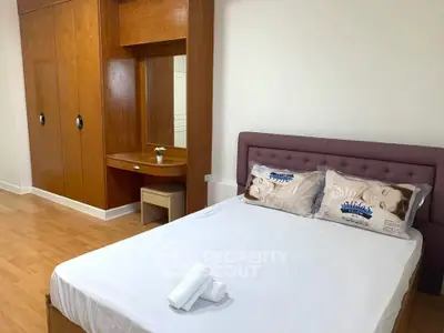 Spacious bedroom with wooden wardrobe and cozy bed setup